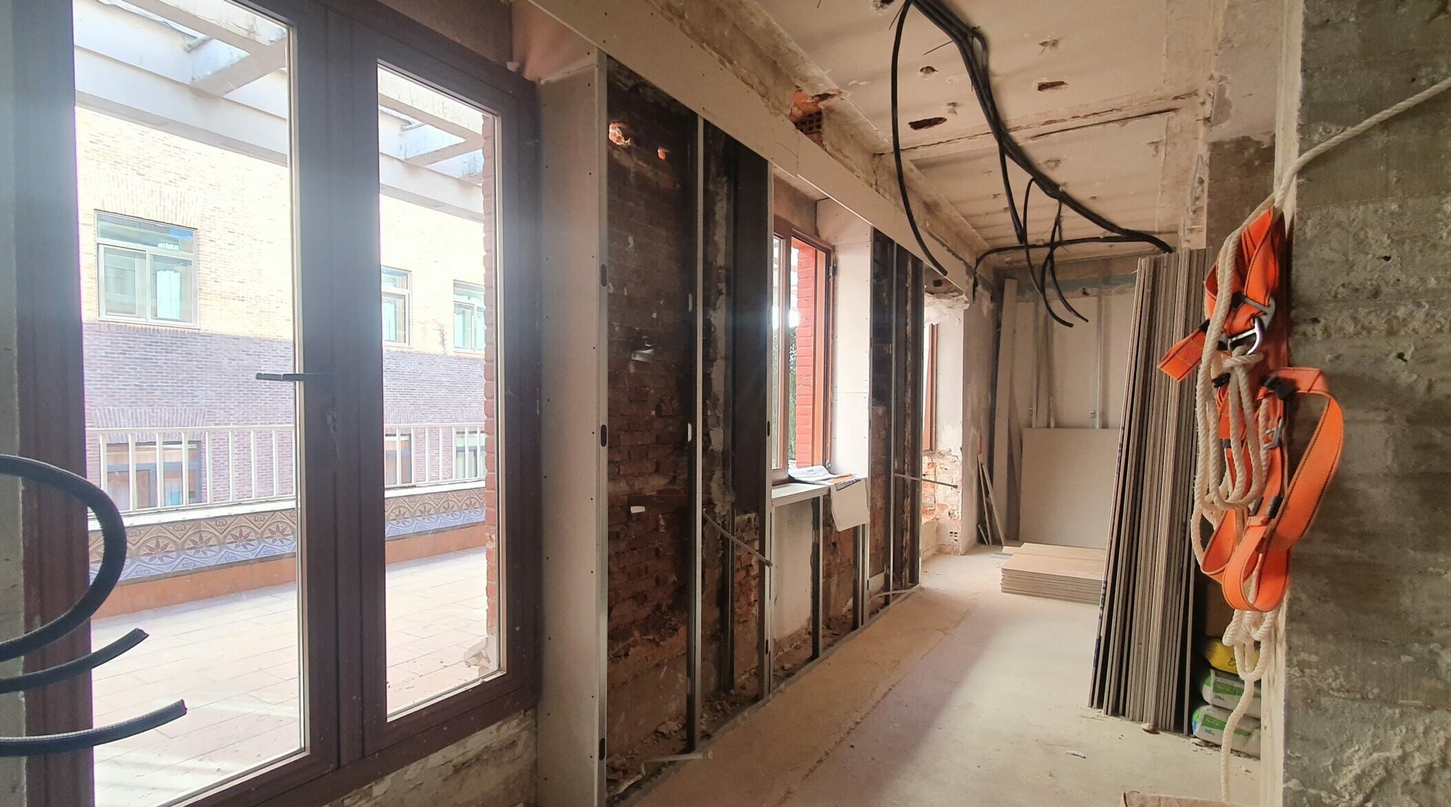 Pasillo en obra con ventanas y materiales de construcción.