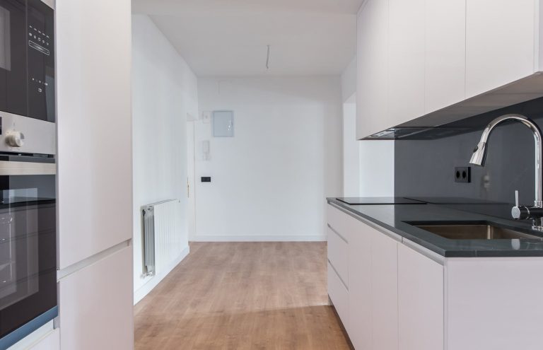 Cocina moderna blanca y negra con electrodomésticos integrados.