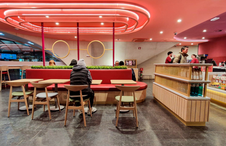 Interior moderno de restaurante de comida rápida con iluminación roja.