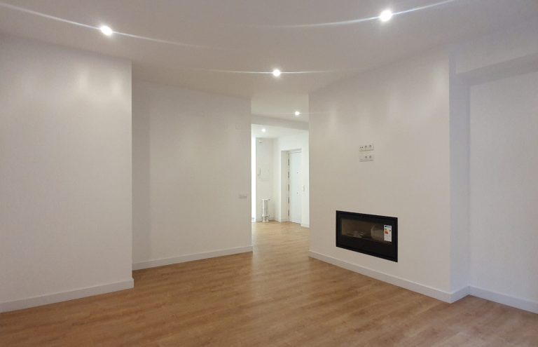 Salón vacío moderno con chimenea y suelo de madera.