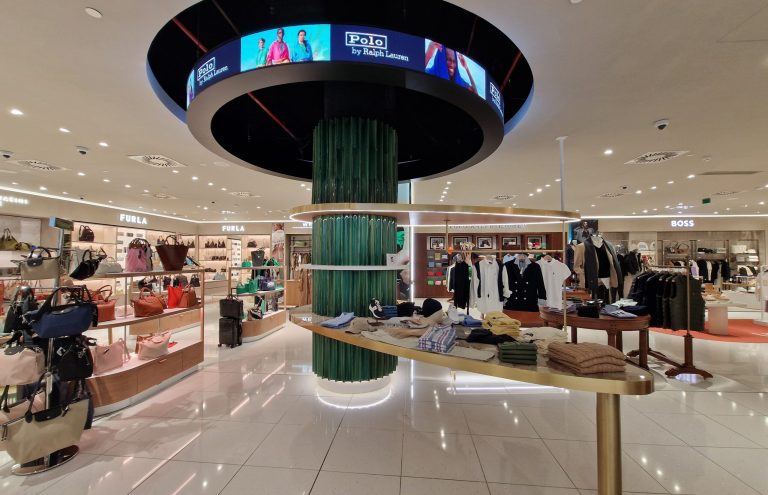Interior de tienda departamental con marcas Furla, Polo Ralph Lauren y Boss.