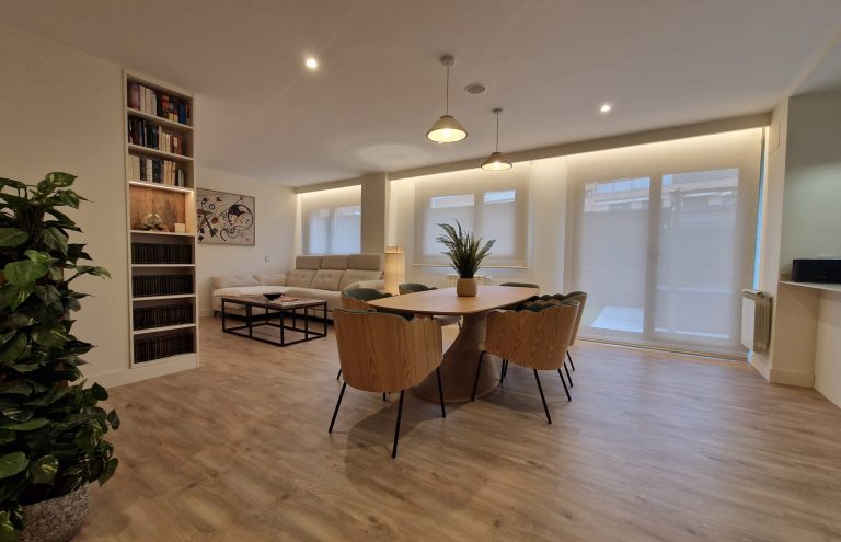 Comedor moderno y luminoso con estantería y plantas.