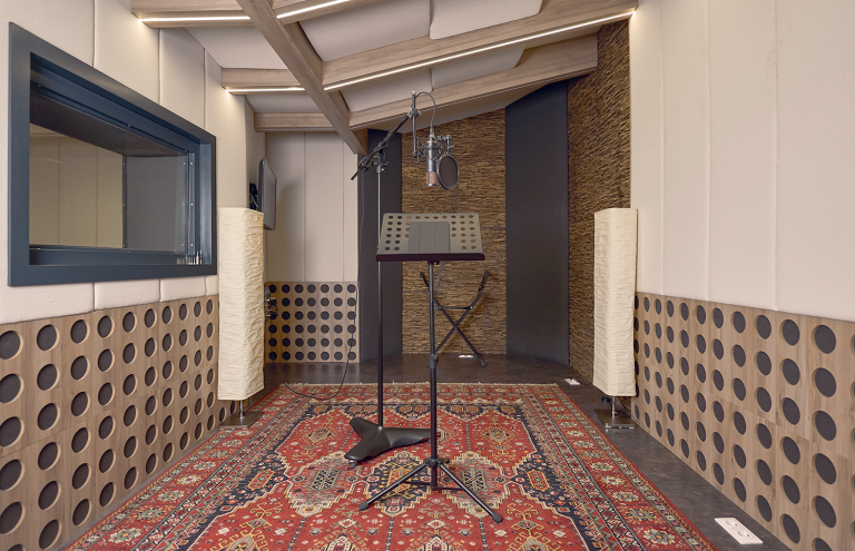 Estudio de grabación profesional con micrófono y cabina vocal.