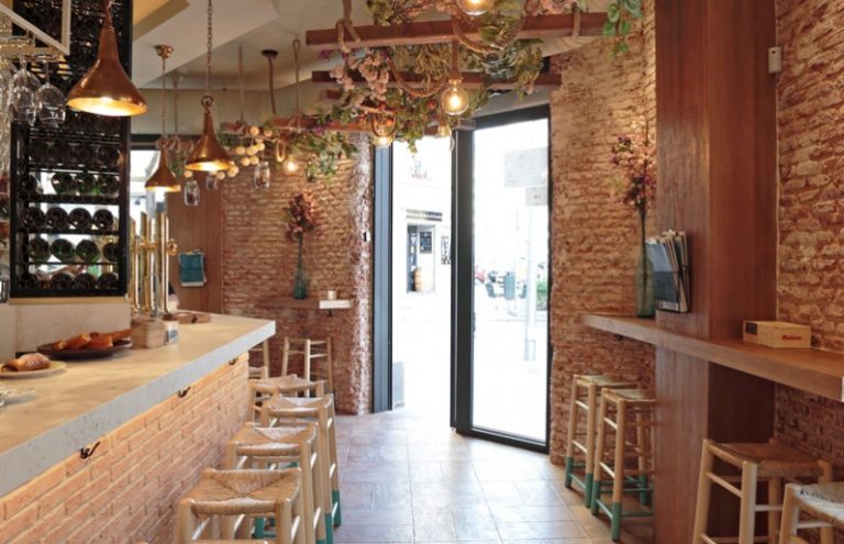 Bar rústico con barra, taburetes y decoración floral.