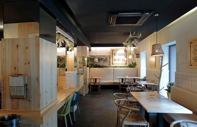 Interior moderno de cafetería con decoración de madera y plantas.